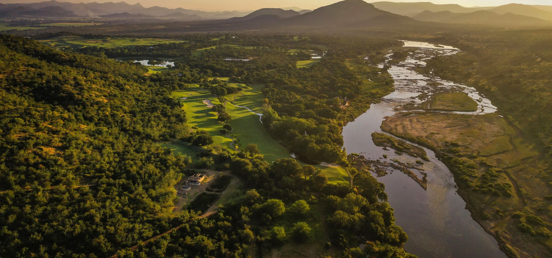 Aerial view of Leopard Creek Country Club at sunrise, its fairways threading the bushveld along the Crocodile River on the Kruger boundary