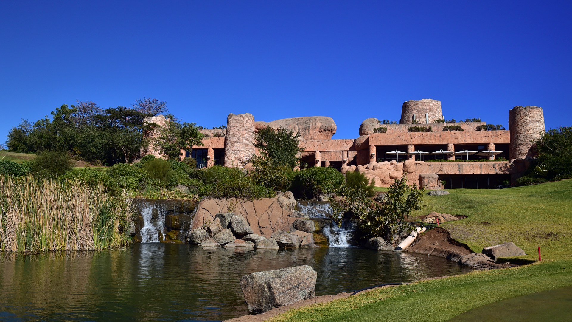 Wide view across the water hazard and green to the Lost City clubhouse and Palace towers at Sun City